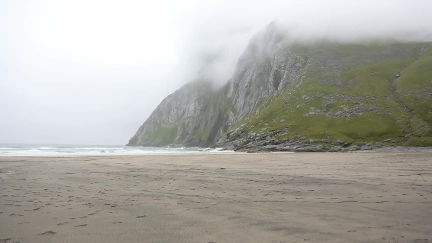 Fog resting on rocky hills on a quiet beach