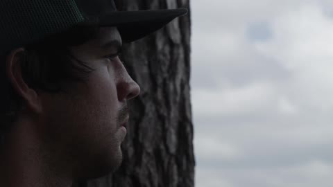 Man standing next to a tree on a cloudy day
