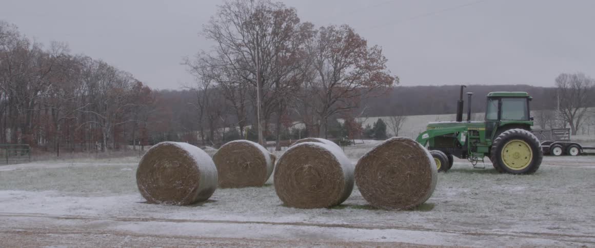 Hay bales and a tractor in a snowy field