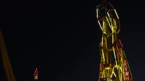 The giant wheel in an amusement park rotates on a dark night