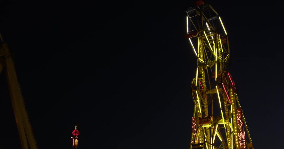 The giant wheel in an amusement park rotates on a dark night