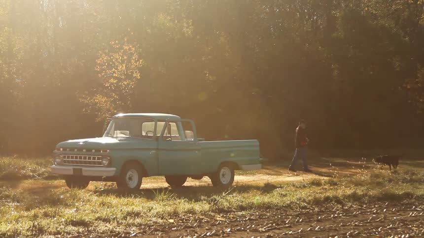 Man walking his dog behind a pickup truck