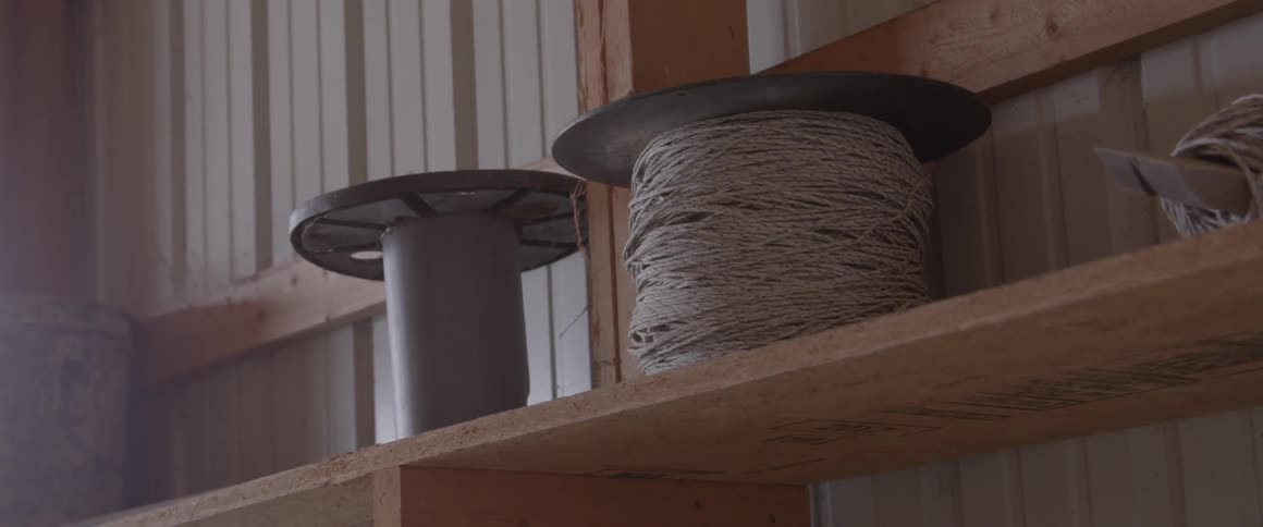 A spool of yarn sits on a wood shelf