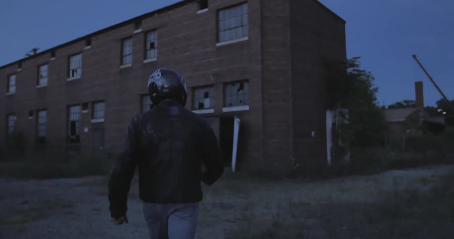 A man with a helmet approaches an abandoned building