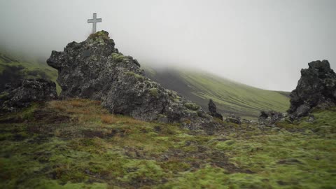A cross sitting atop a rocky mountain