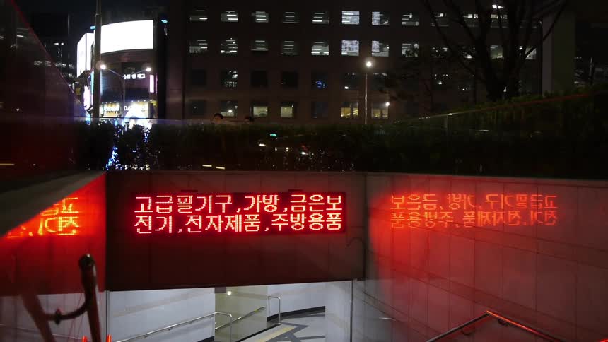 Text scrolls across a billboard placed at the subway entrance