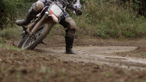A person rides a dirt bike around a curve on a dirt track