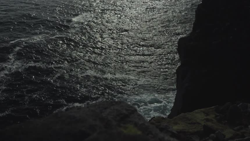 Aerial view of water crashing against rocks below