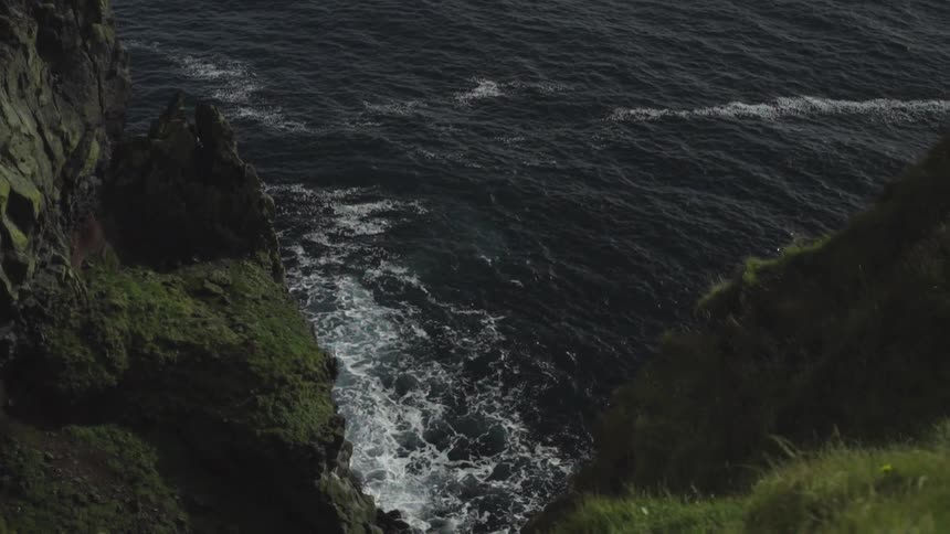 Edge of a rocky and grassy cliff overlooking the ocean