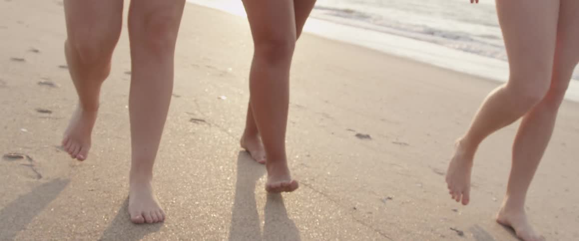 View of the legs of three woman walking on a beach