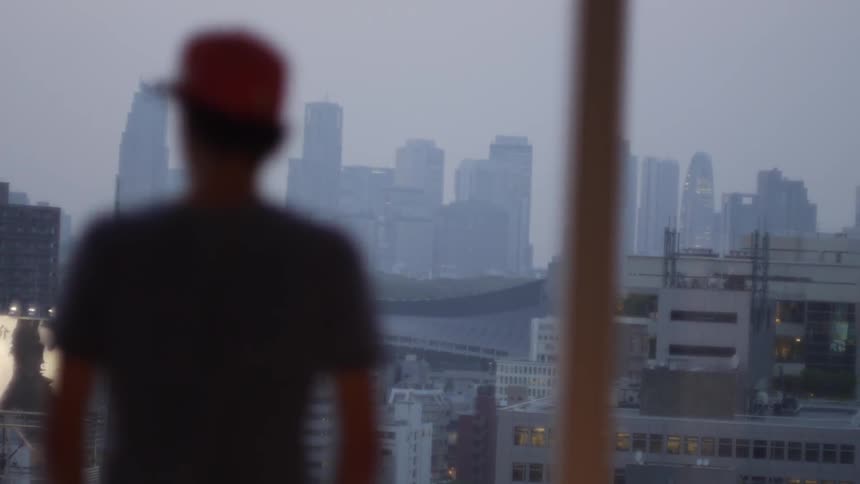 A man gazes out a window at the Tokyo cityscape beyond