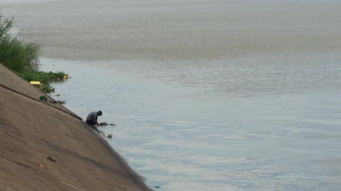 A person washing clothes in the waters of a lake