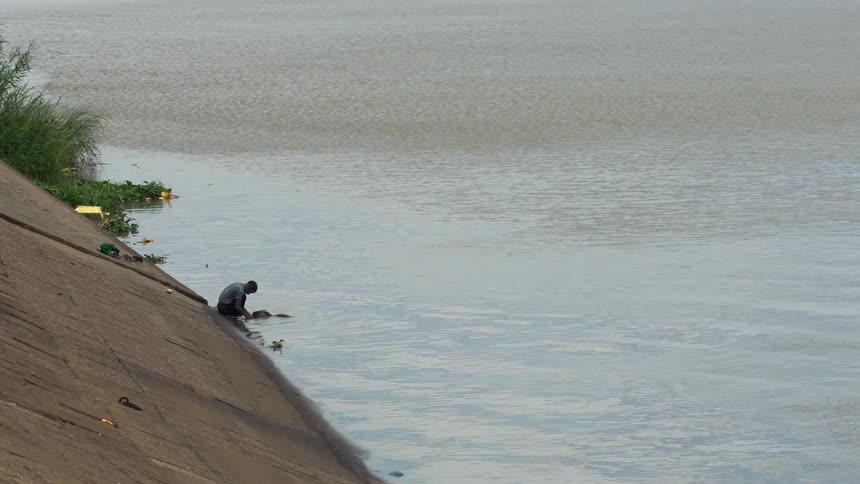 A person washing clothes in the waters of a lake