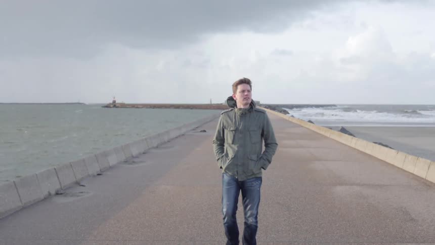 Man walking on road along water