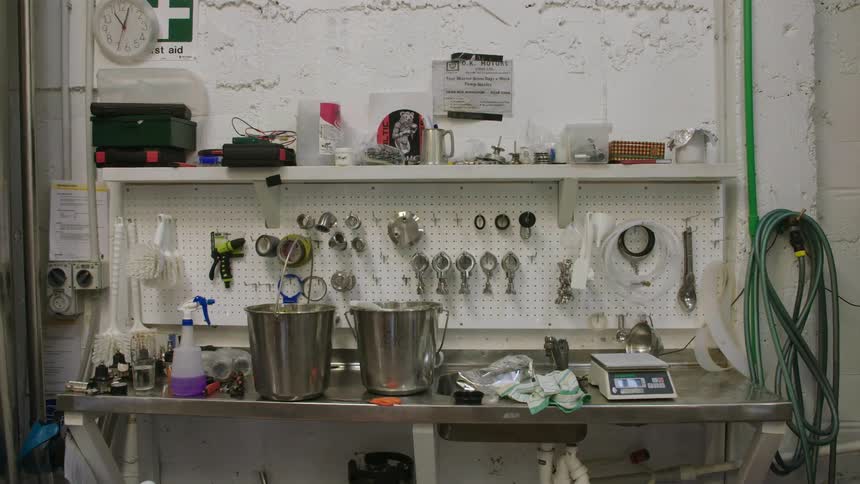 A shop bench with hoses, a scale, buckets and various other implements