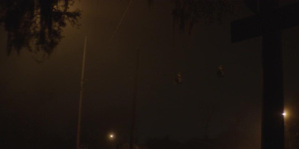 A traffic light blinking red on a foggy and dark evening