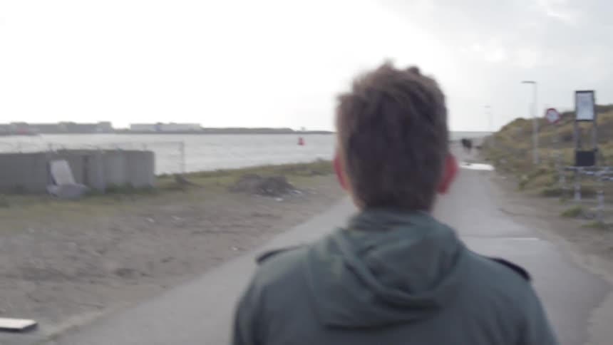 A man walks down a beachside road