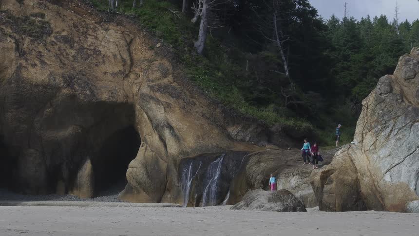 People walk near a cave on the beach