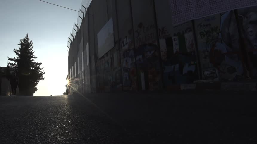 The sun shines on a graffitied wall