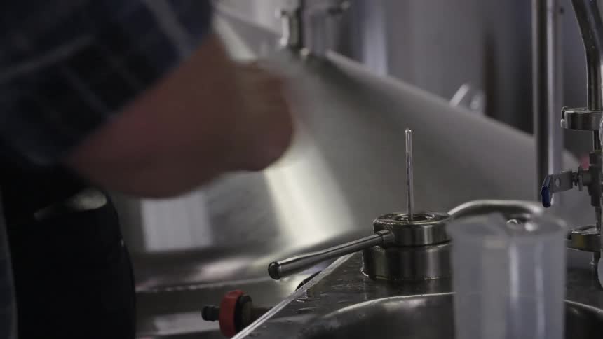 Person checking the temperature of the liquid in a container