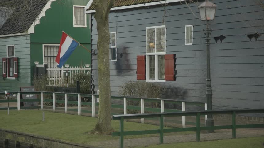 A flag hangs from a house and billows in the wind