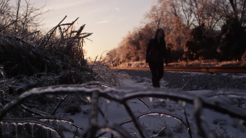 Woman walking next to train tracks on a chilly day