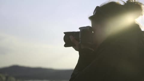 A woman is taking photographs of a rocky coastline