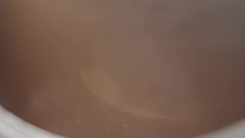 Steam rises from a swirling brown liquid