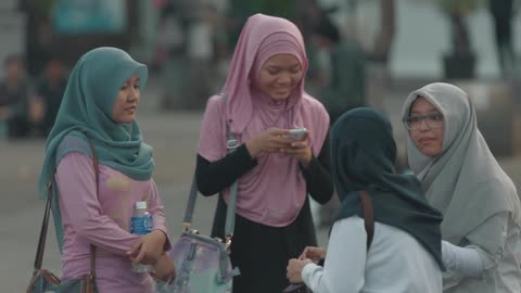 Four women wearing hijabs are talking and laughing