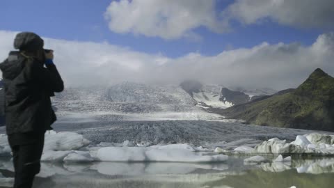 A woman photographs a snow-covered mountain