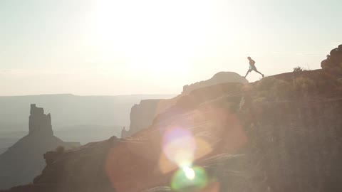 A long-shot view of a man running and jumping on a mountain ridge