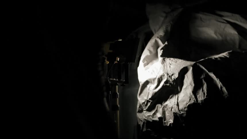 Man covering a car with a tarp in a dark garage