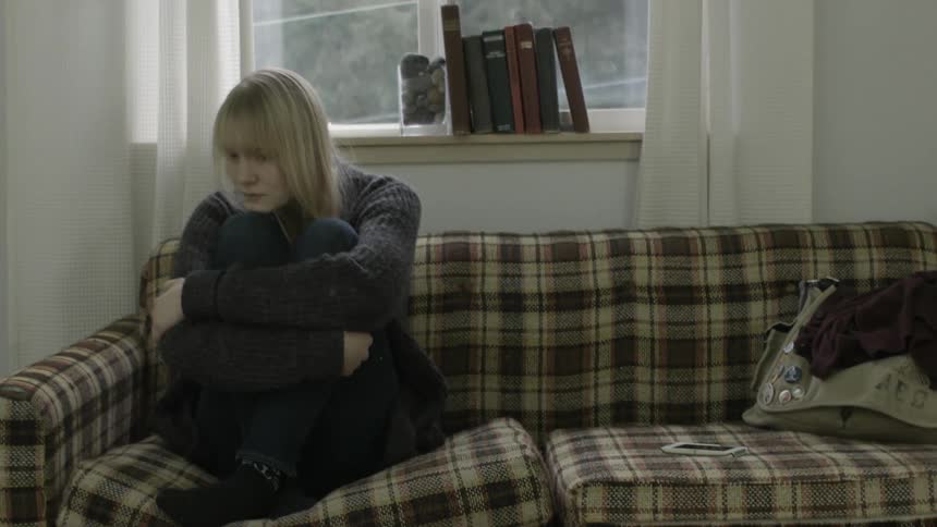 A worried woman sitting alone on a couch
