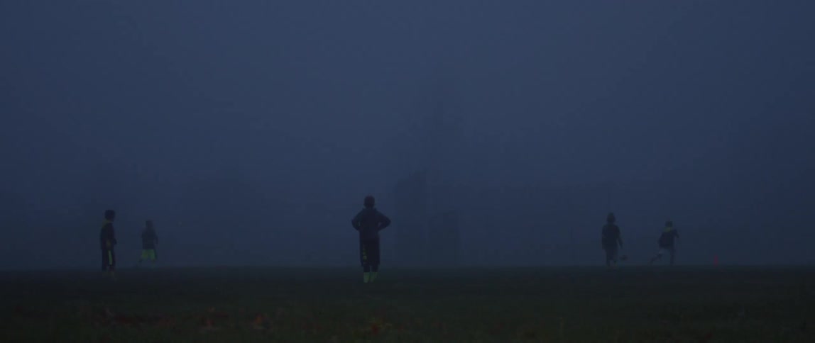 A group of kids play ball at dusk