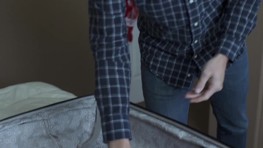 Man taking clothes from closet and putting them in suitcase