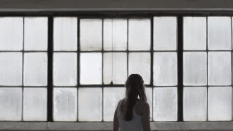 A young woman walking by some windows