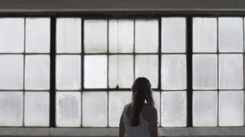 A young woman walking by some windows