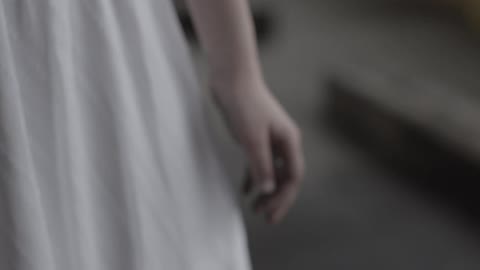 A woman in a white dress stands still