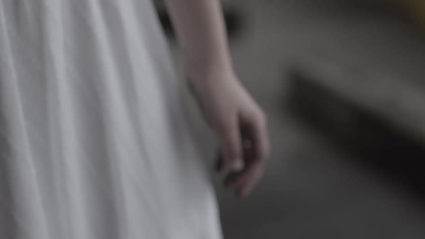 A woman in a white dress stands still