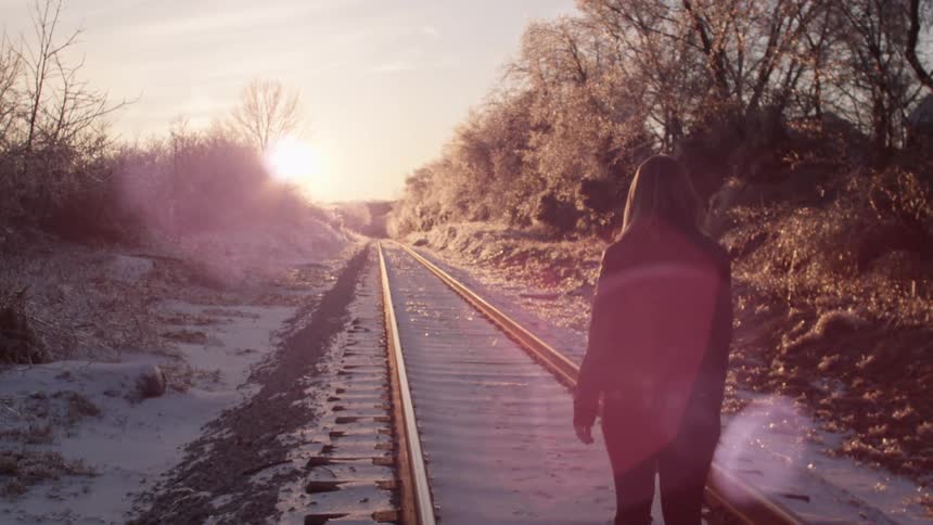 A woman walking along the train tracks