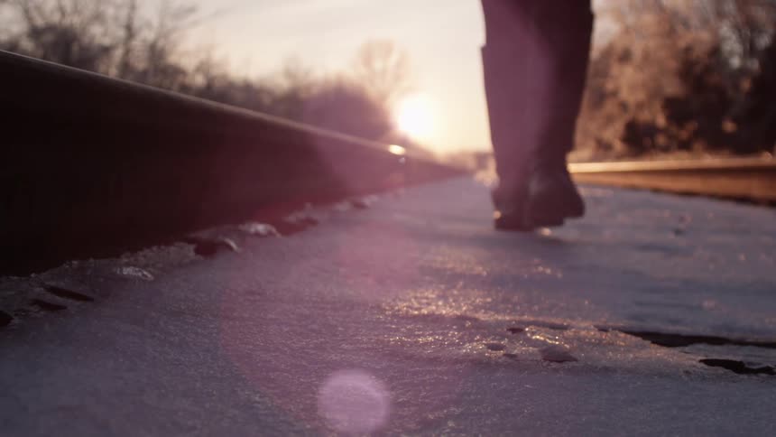 A person walks on train tracks in the snow