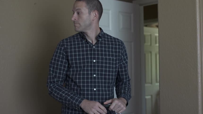 A man lifts a suitcase off of a bed