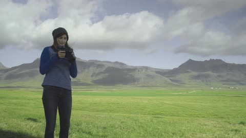 Woman standing in a pasture taking pictures