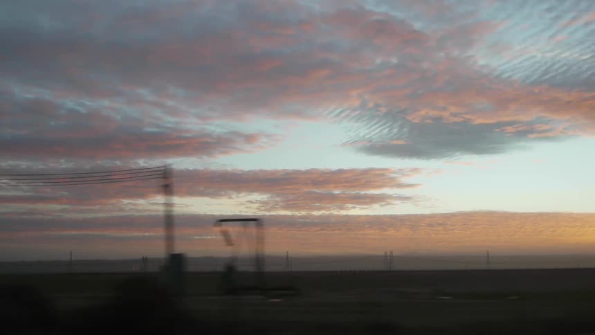 A vehicle drives across an expanse as the sun sets