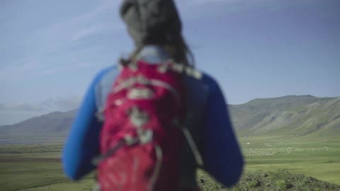 A woman with a backpack hikes through a valley