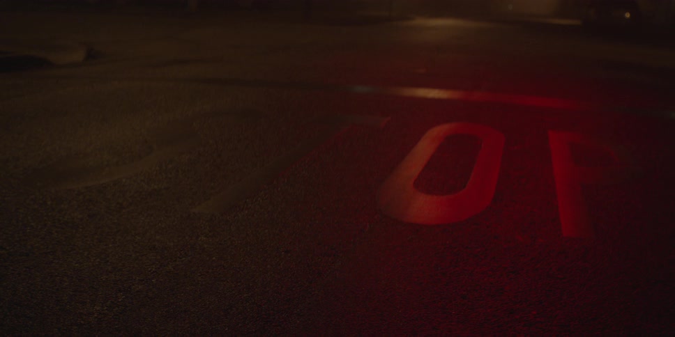 Stop sign markings painted onto the street being illuminated by a red, flashing traffic signal