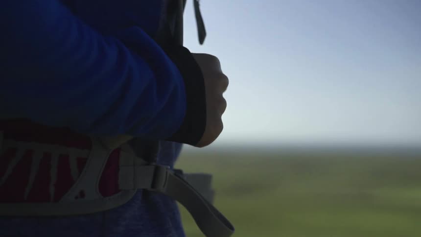 A person wearing a backpack is standing on the edge of a cliff