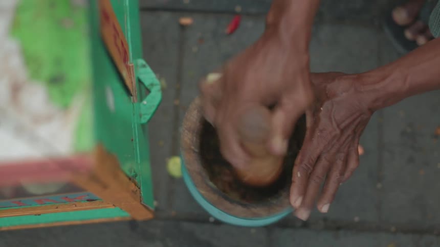 An aged person is manually grinding spices