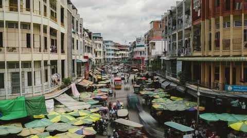 City with umbrellas and stands on the sidewalks as people walk and drive up and down the street