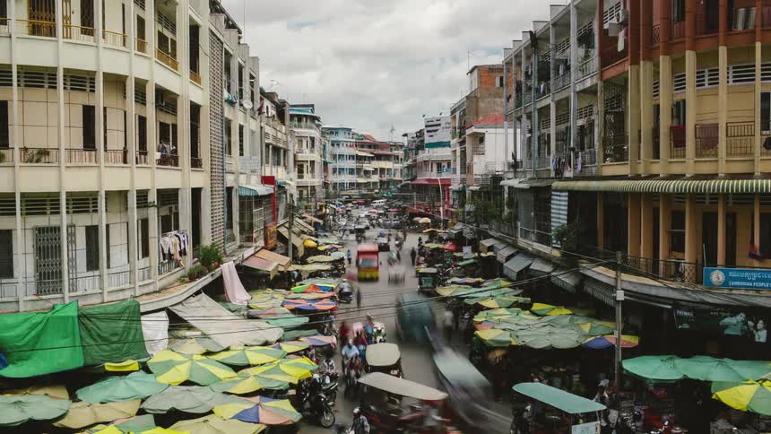 City with umbrellas and stands on the sidewalks as people walk and drive up and down the street